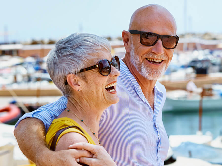 Mature couple in transitions lenses smiling by a marina